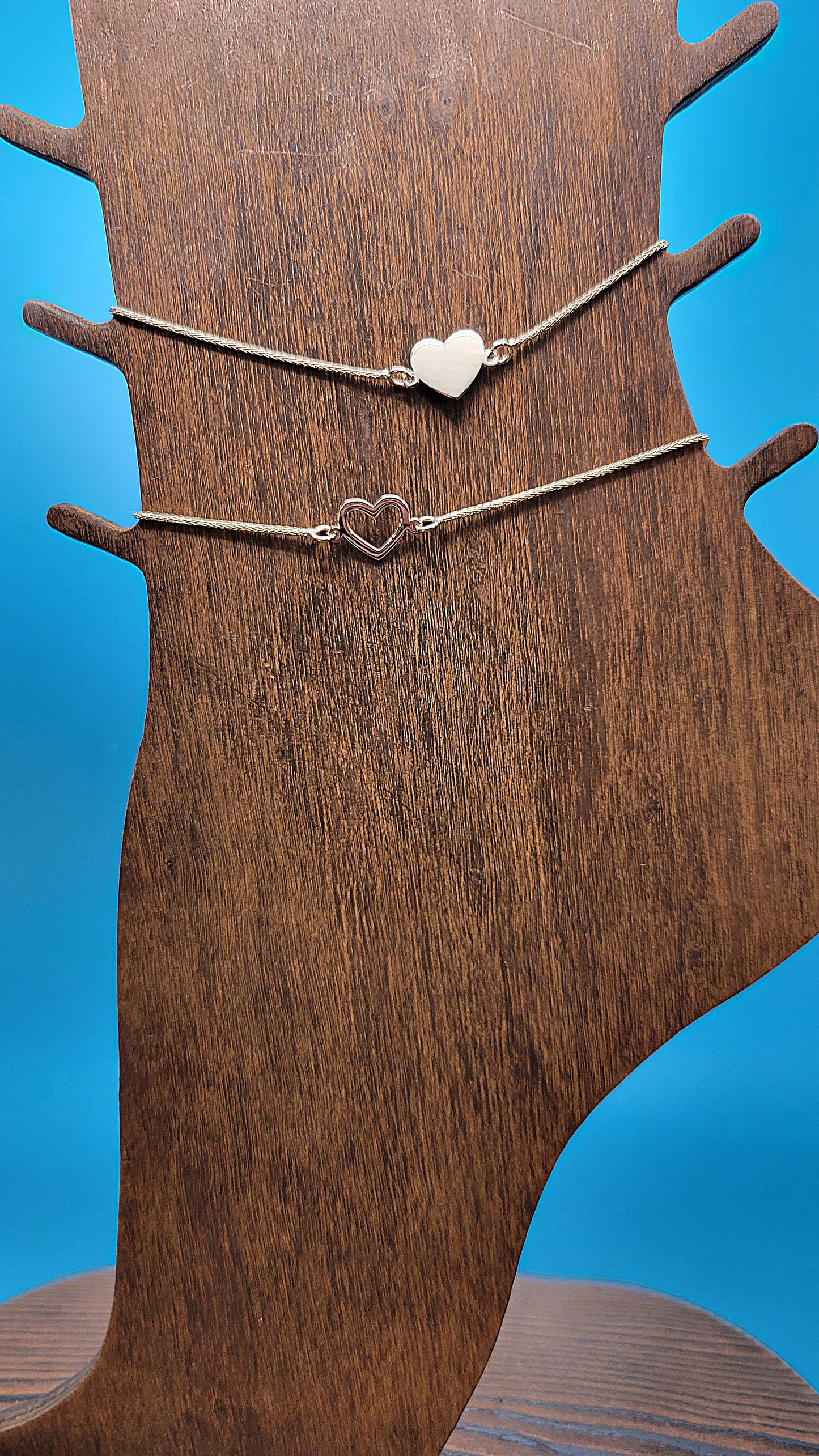 14k gold Hollow and Solid Heart Anklets on wooden foot display on blue color background closer look.