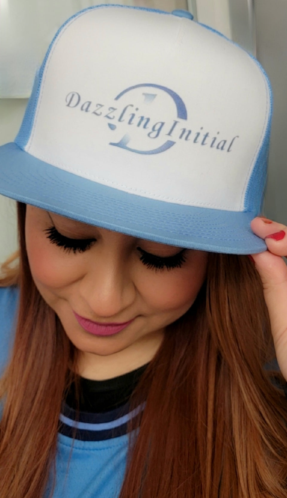 Model in a light blue and white hat with our logo, looking down. Image 1 of 4, main page.
