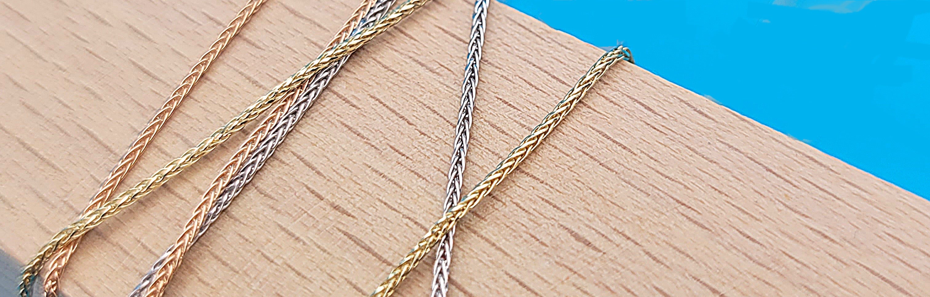 Slide 1of5: Our round wheat style chains in rose, white and yellow gold on top of wood beam